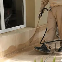 General pest control technician spraying exterior perimeter around a home in St Paul, MN