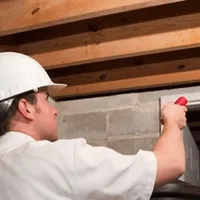 Termite inspection technician checking a basement wall and framing for termite activity in St Paul, MN